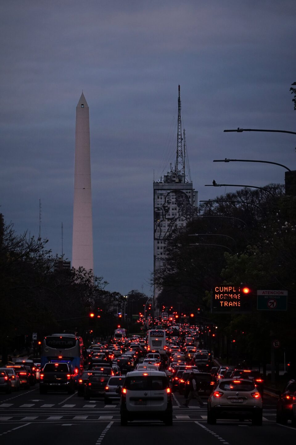 Obelisco al anochecer sobre una avenida con tráfico y luces de coches