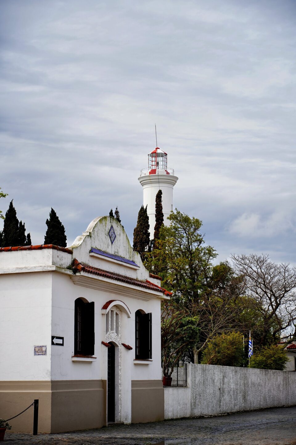 Faro de Colonia del Sacramento tras una casita blanca de tejado rojo