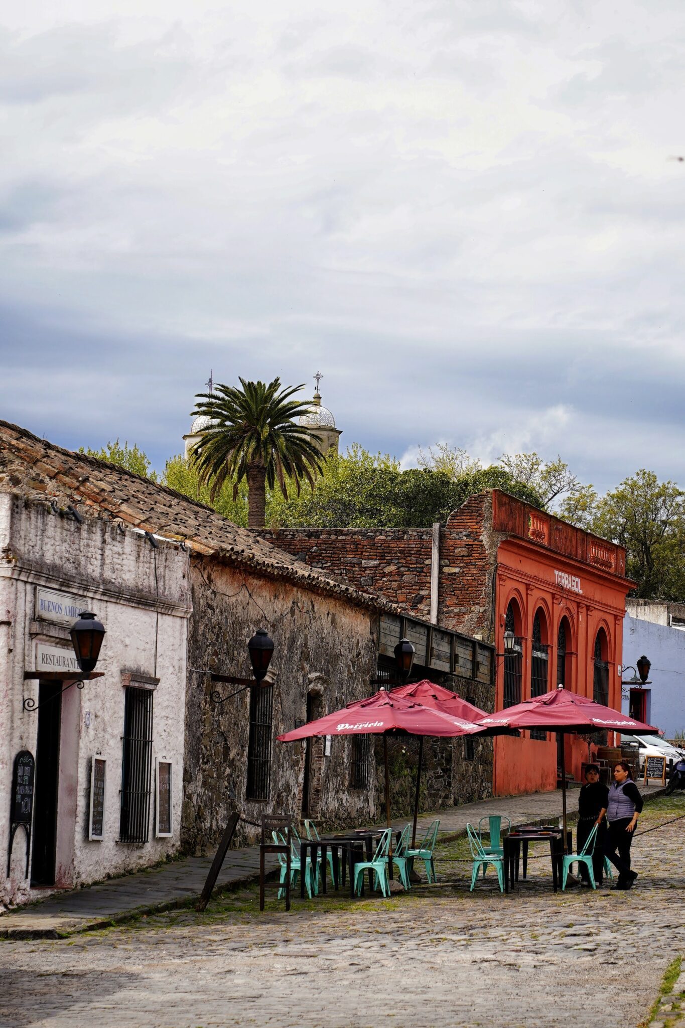 Calle empedrada de Colonia del Sacramento con casas de piedra y terrazas con sombrillas rojas
