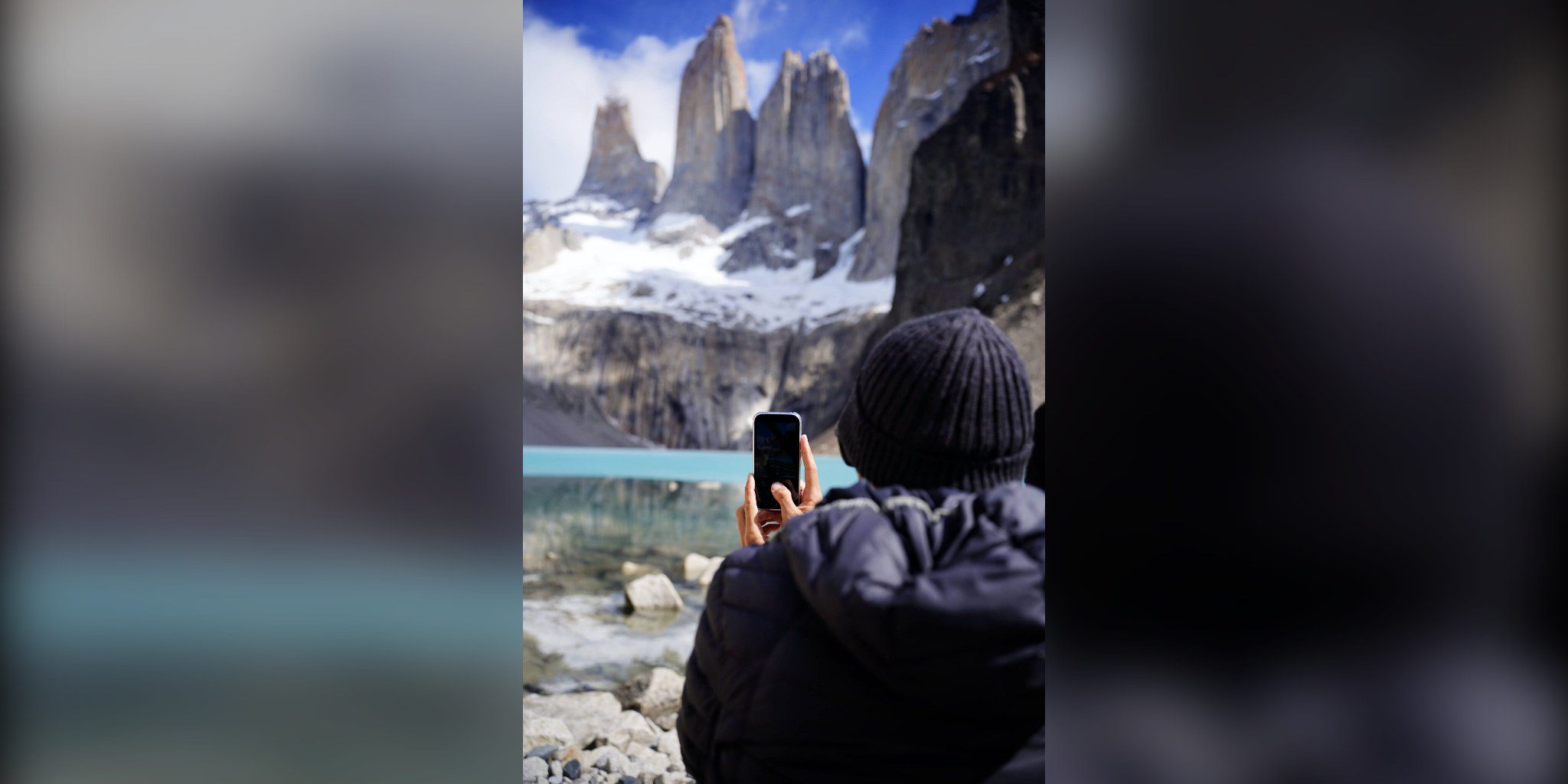 Persona con gorro fotografía con el móvil las Torres del Paine y la laguna turquesa